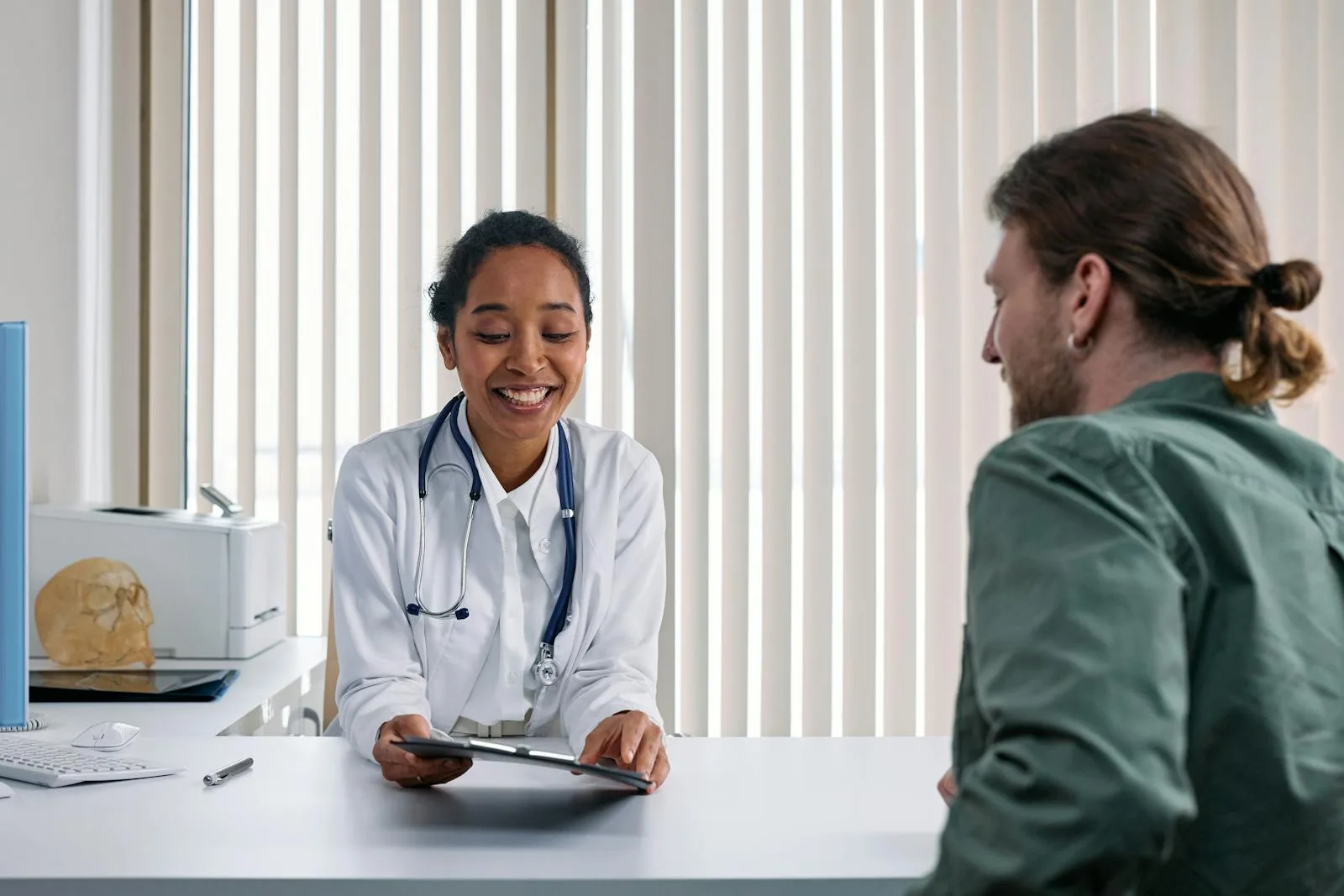 Smiling clinician reviewing notes with a patient at a clinic desk